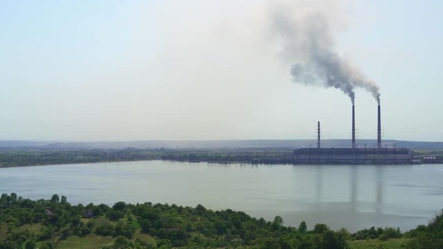 2017 year Ukraine. Burshtyn thermal power plant on the background of the reservoir. Sunny summer day Black smoke spreads around the surrounding villages and poisons them.