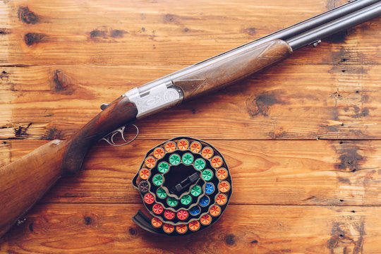 Hunting equipment. Shotgun and hunting cartridges  on wooden table.