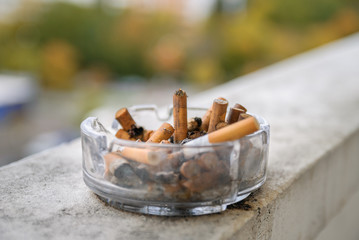 Wet cigarette butts in ashtray in balcony