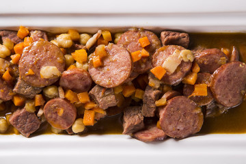 South American cuisine: Puchero soup with sausage. close-up in a pot on the table.