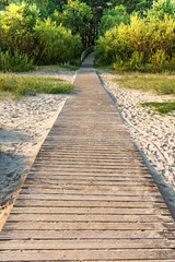 Fototapeta na wymiar perspective of wooden path on a beach which leads to a forest. Baltic sea, Latvia.