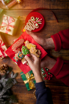 Hands of little boy and woman decorating Christmas cookies