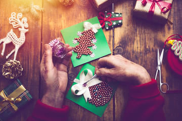 hands of senior woman making handmade New Year's or Christmas gifts and decorations with vintage effect