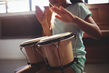 Mid section of girl playing bongo drums
