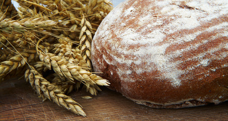 Fresh bread and ripe wheat on the wooden board