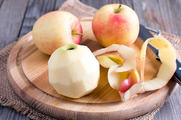 Peeling an apple with a knife on a wood background