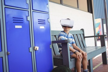 Boy using virtual reality glasses while sitting on bench by