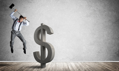 Determined banker man in empty concrete room breaking dollar figure