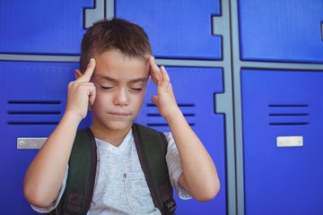 Boy suffering from headache against lockers