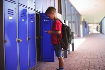 Boy using mobile phone by open locker