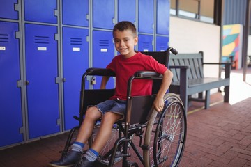 Portrait of boy sitting on wheelchair in corridor