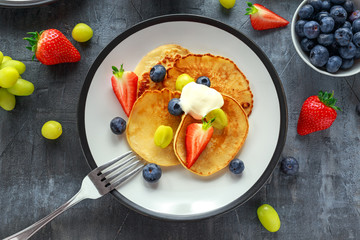 Homemade Pancakes with Blueberry, Strawberry, green Grape and honey syrup. served on plate