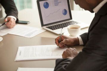 Close up photo of african american businessman sitting at office desk in front of laptop with...