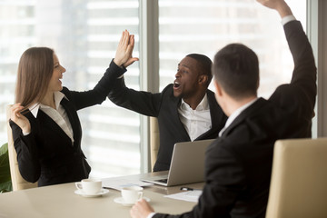 Excited office workers giving high five celebrating wages or sales increase, successful deal,...