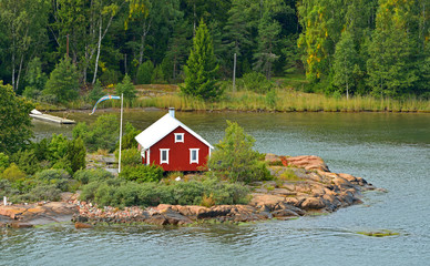  Life on small islands. Red wooden house with flag of Aland Islands, Finland