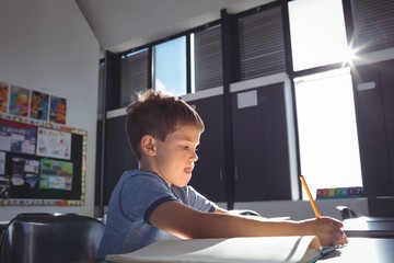 Boy writing on book in school