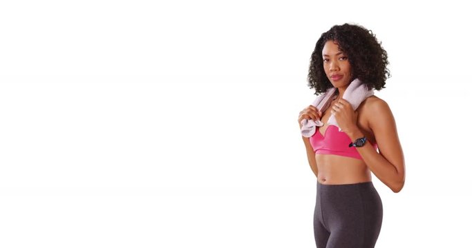 Black female in workout clothes holding towel around neck, smiling in studio