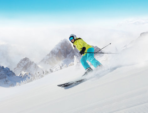 Young woman skier running down the slope in Alpine mountains