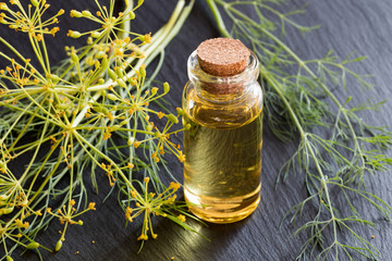 A bottle of dill seed oil on a dark background