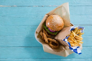 Overhead view of burger with French fries and onion rings in - obrazy, fototapety, plakaty