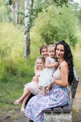 Fototapeta premium Beautiful young family with two daughters walking in the forest in summer