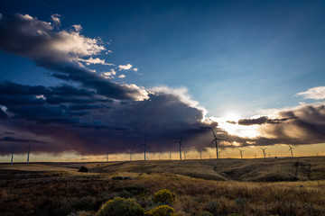 Fototapeta na wymiar Wind mill turbines producing green renewable power at sunset.
