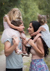 Obraz premium Beautiful young family with two daughters walking in the forest in summer