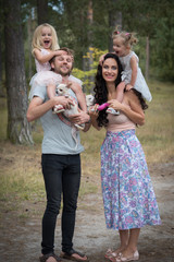 Fototapeta premium Beautiful young family with two daughters walking in the forest in summer