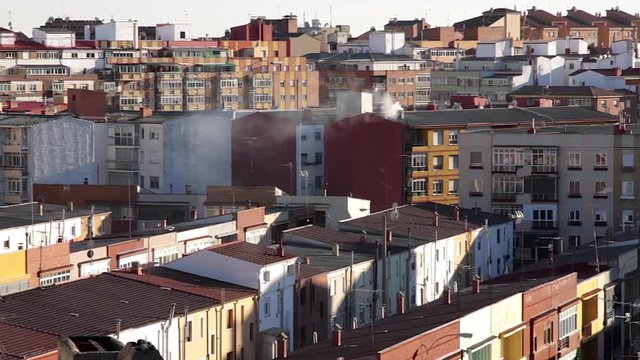 Azoteas, tejados y edificios a distintos niveles de una ciudad, con chimeneas echando humo y antenas de television en los tejados