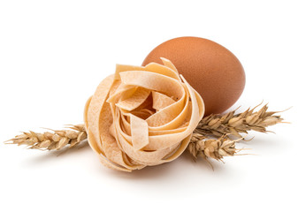 Italian pasta fettuccine nest, egg and wheat ears still life isolated on white background