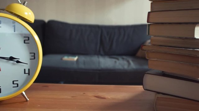 Dolly shot of shelf with big yellow clock and stack of books