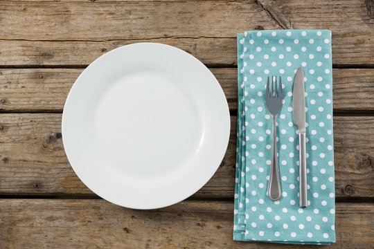 Overhead view of empty plate by napkin and eating utensils