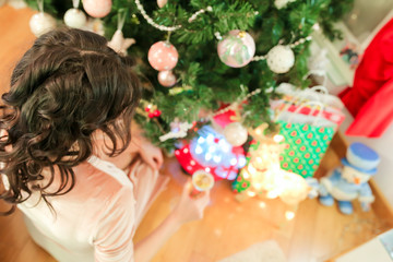 Fototapeta na wymiar Happy young woman on Christmas eve near festive fir-tree