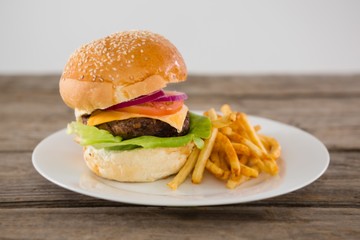 Cheeseburger served with French fries in plate