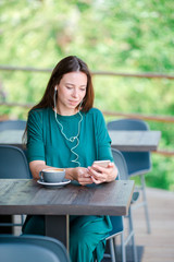 Young woman with smart phone while sitting alone in coffee shop during free time