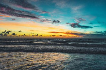 first light over the ocean creating a colorful sky just before sunrise with reflection on the waves