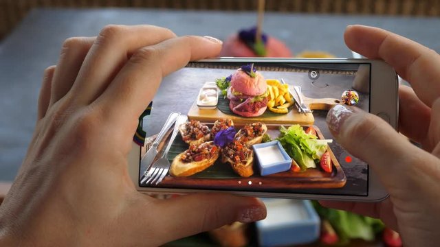 Female Hand Taking Pictures With Smartphone Of Food: Burger With Fries. Closeup.
