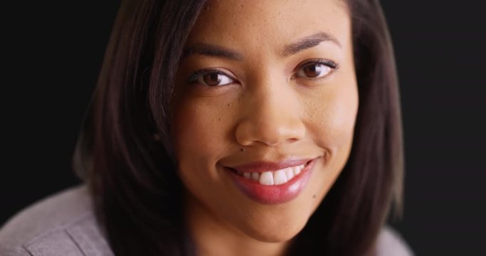 Close up of beautiful black female with bright smile on black background