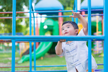 Obraz premium Asian boy hang the metal bar at outdoor playground.