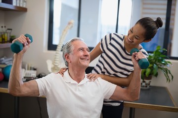 Smiling female doctor looking at senior male patient lifting