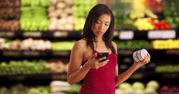 Pretty black female takes photo of nutrition label on tuna can at supermarket