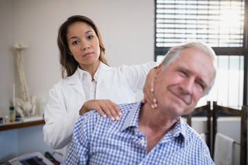 Portrait of female therapist giving neck massage to senior male