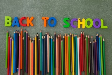 Block letters and color pencils arranged on chalkboard