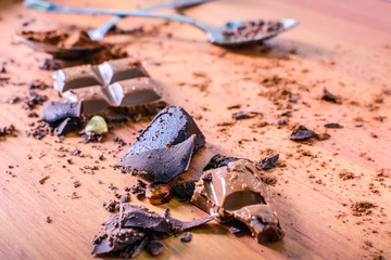 Chocolate sticks, cut into pieces, Grated, shredded, Cocoa powder is on the table.