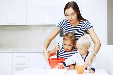 Adorable happy family makes cakes together on your white kitchen.