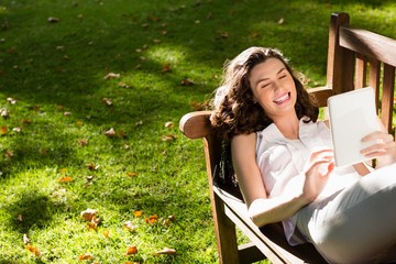 Woman lying on bench and using digital tablet in garden on a