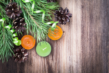 Pine branch, candles, cones on wooden background with copyspace.