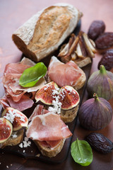 Close-up of bruschettas with prosciutto, fig fruits and dates, selective focus
