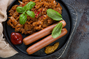 Above view of braised cabbage with sausages served in a frying pan, close-up