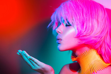 Fashion model woman in colorful bright lights with trendy make-up, manicure and haircut
